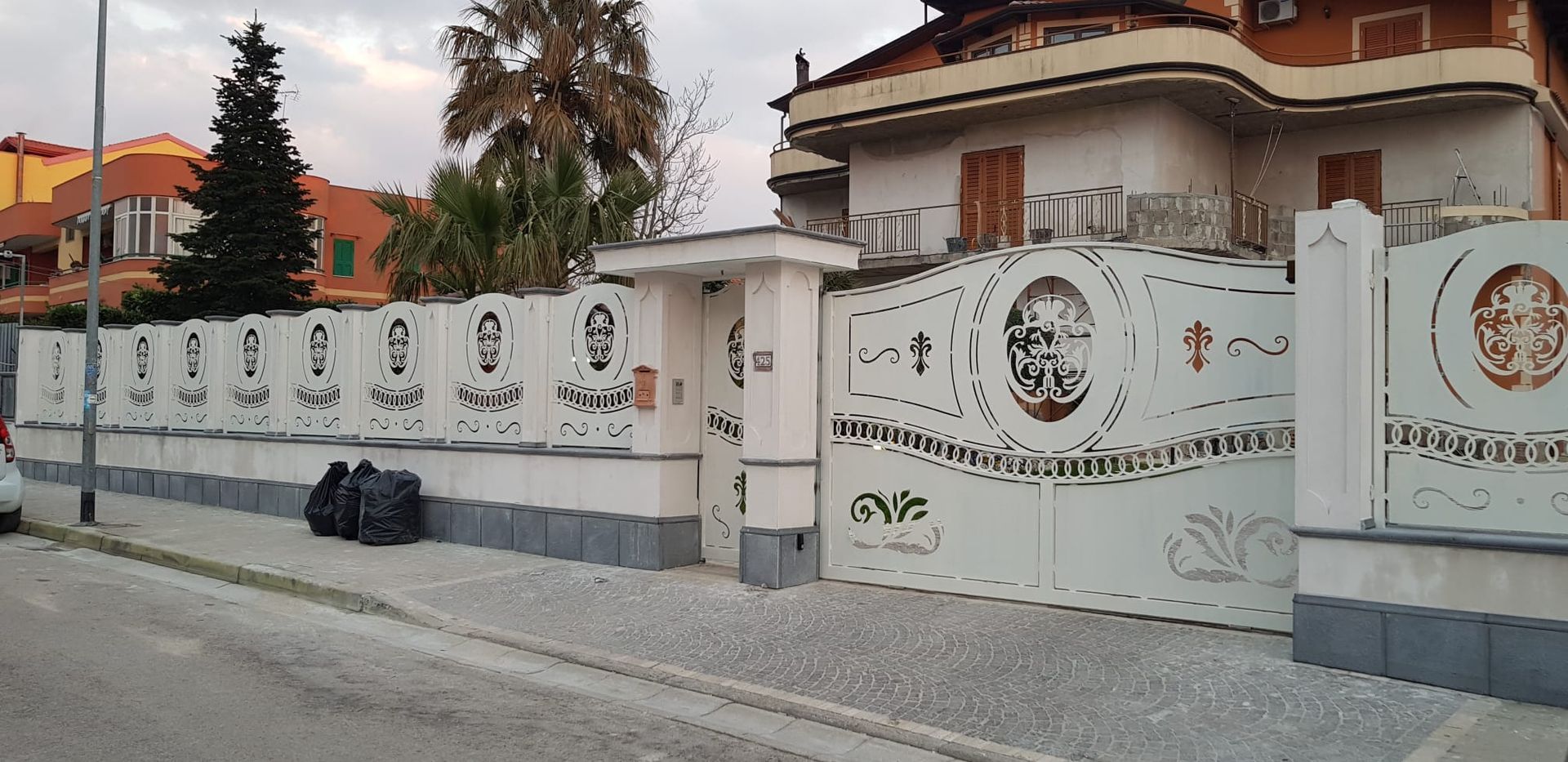 Muro decorativo bianco e cancello di una casa in una tranquilla strada residenziale al crepuscolo