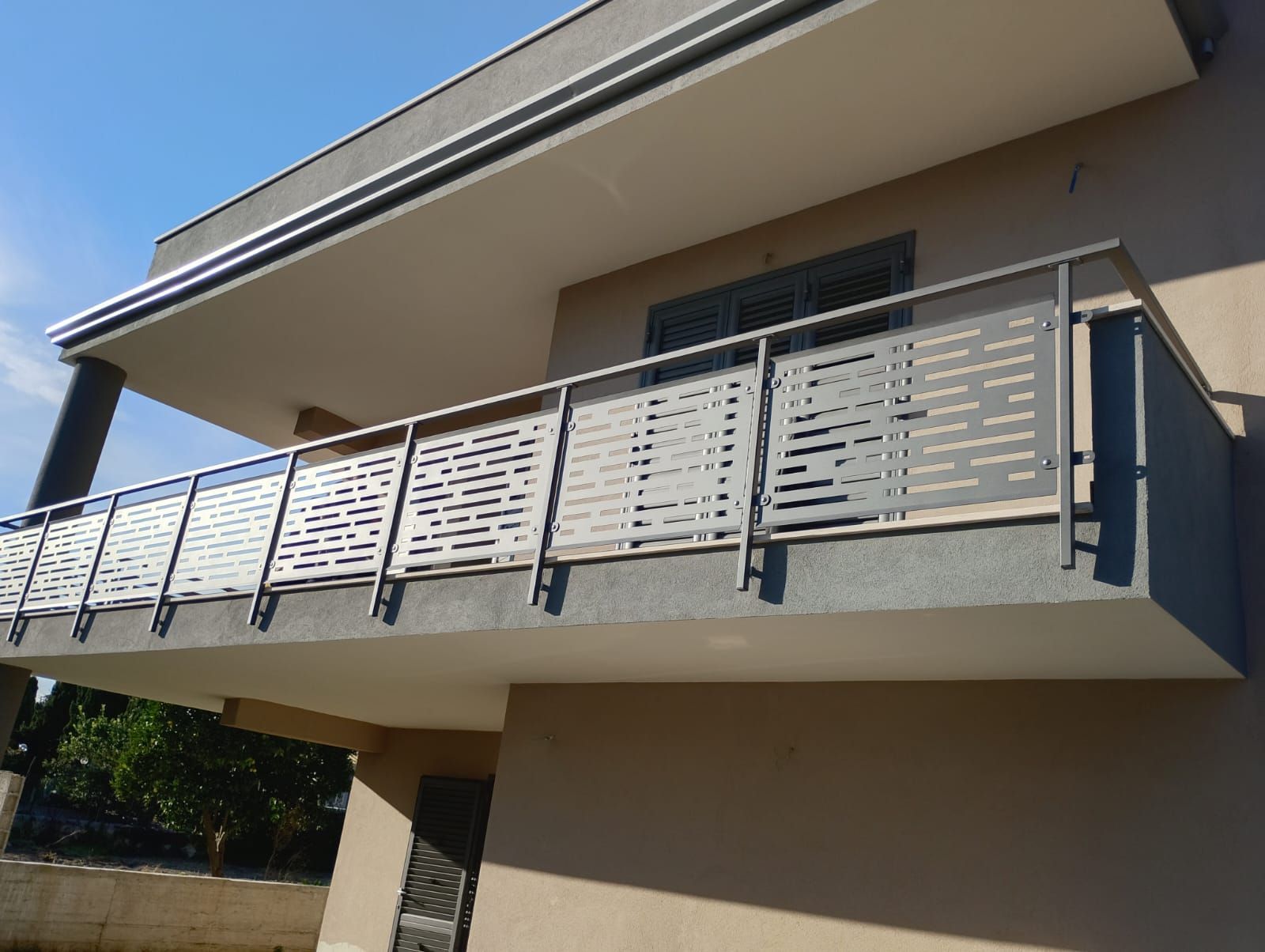 Balcone di casa moderna con ringhiera in metallo grigio e pareti esterne beige.