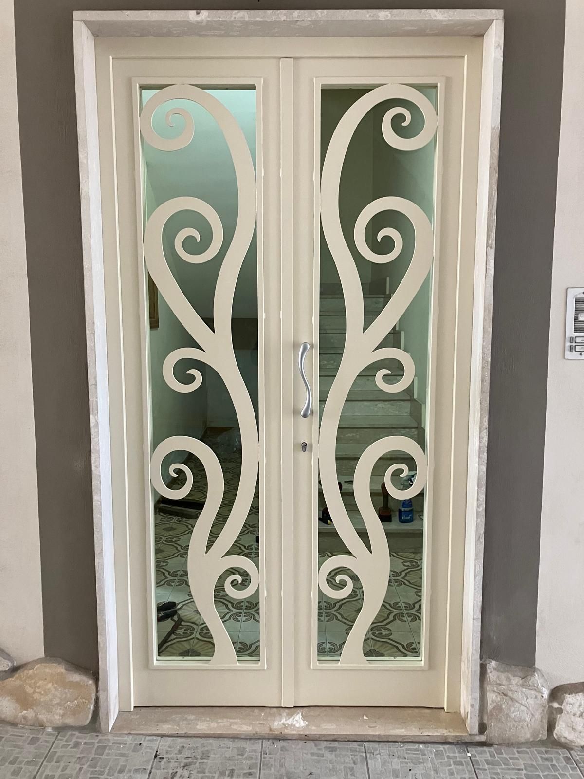 Doppie porte bianche con decorazioni a volute e vetro satinato incastonate in un muro di pietra