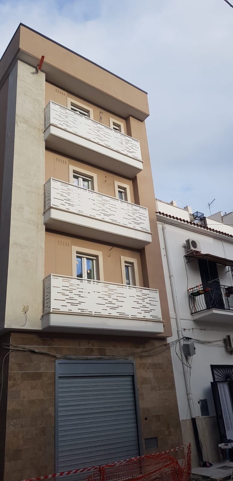 Alto palazzo residenziale beige con balconi e una serranda grigia chiusa al piano terra.