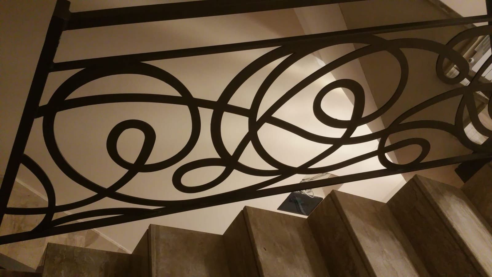 Ringhiera decorativa in ferro battuto nero sopra una scala in legno.