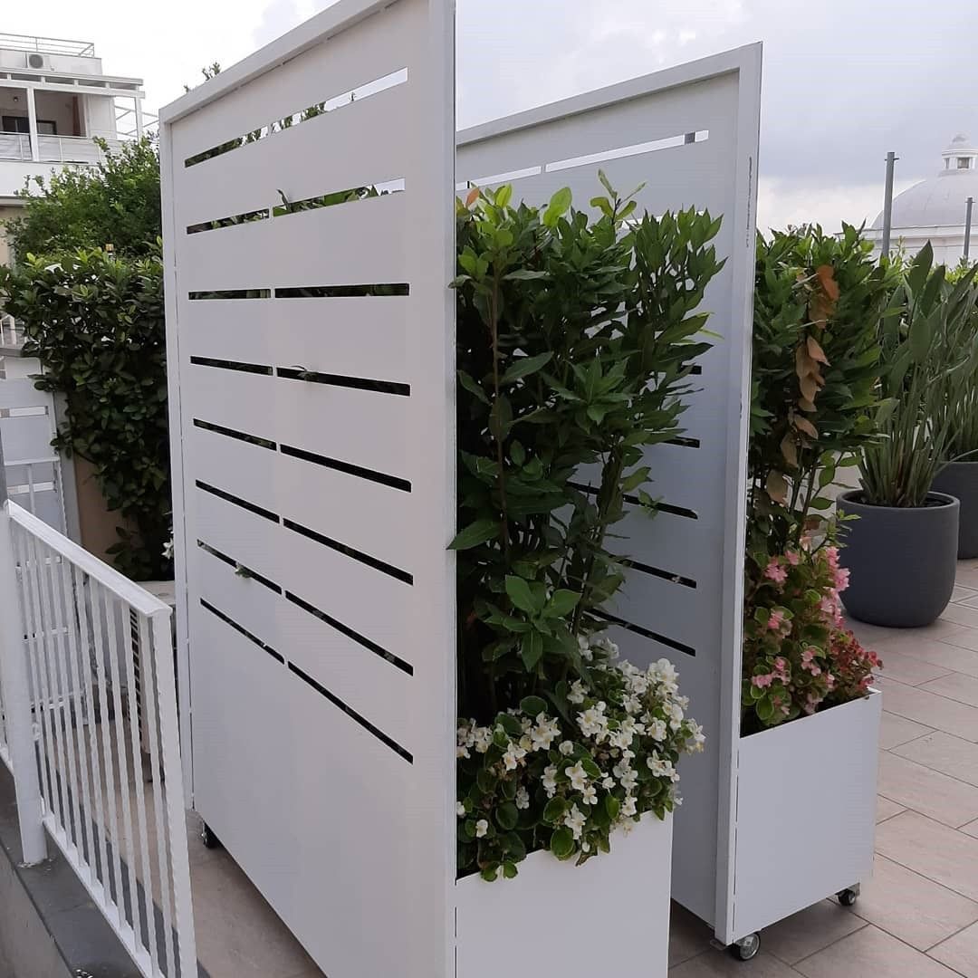 Fioriere a doghe bianche con rigogliosi fiori verdi e bianchi su una terrazza.