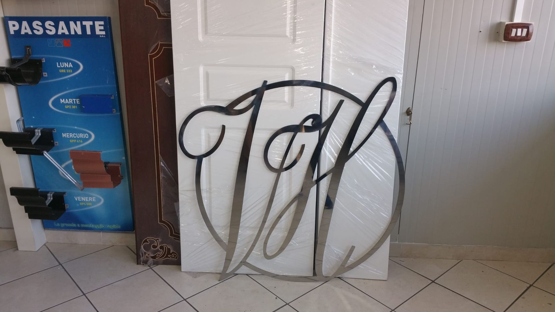 Oggetto circolare bianco con graffiti neri appoggiato a una parete piastrellata accanto a una porta blu
