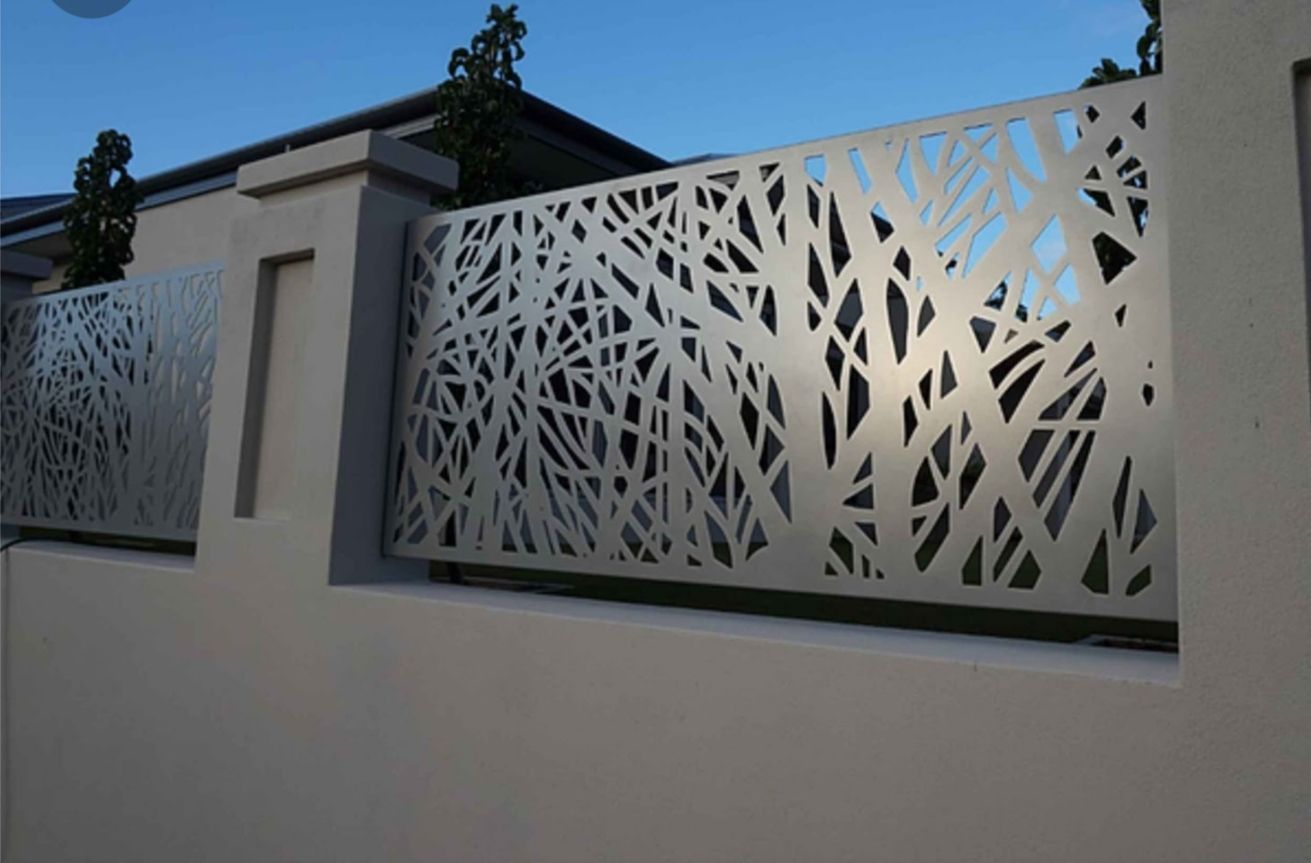 Pannelli decorativi in metallo bianco con intagli a forma di foglia su un muro di stucco all'aperto al crepuscolo