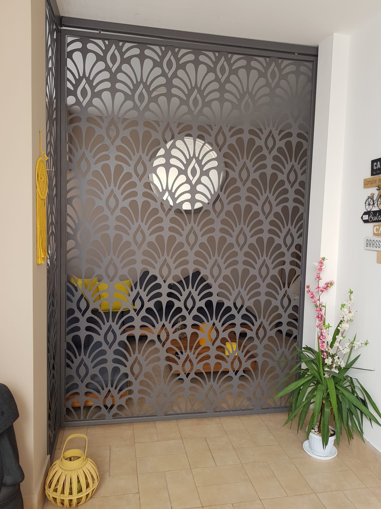 Cancello decorativo in metallo con intagli floreali, pianta in vaso e lanterna in vimini in un ingresso interno
