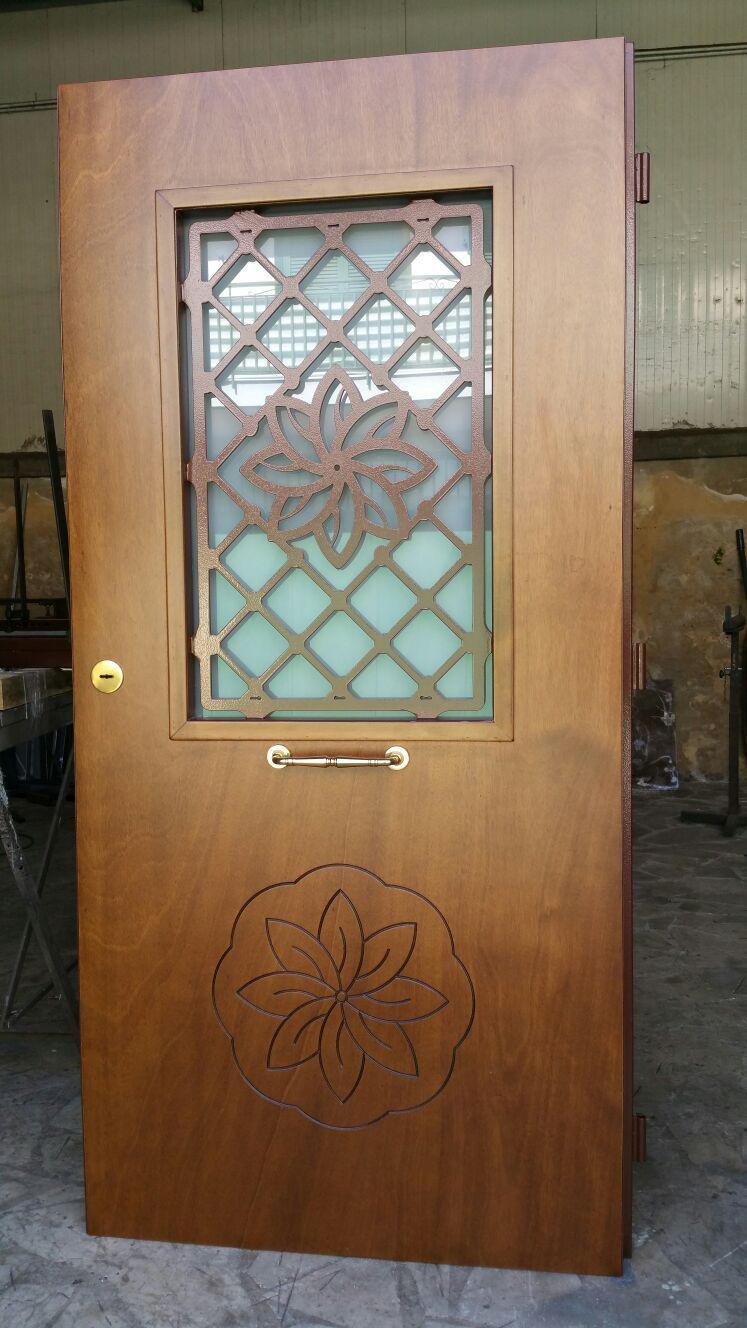 Porta in legno con una piccola finestra decorativa in vetro e intagli floreali.