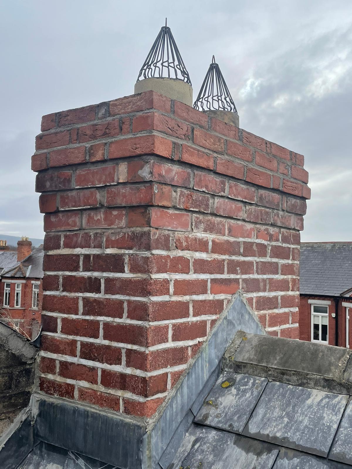 A brick chimney is on the roof of a building.