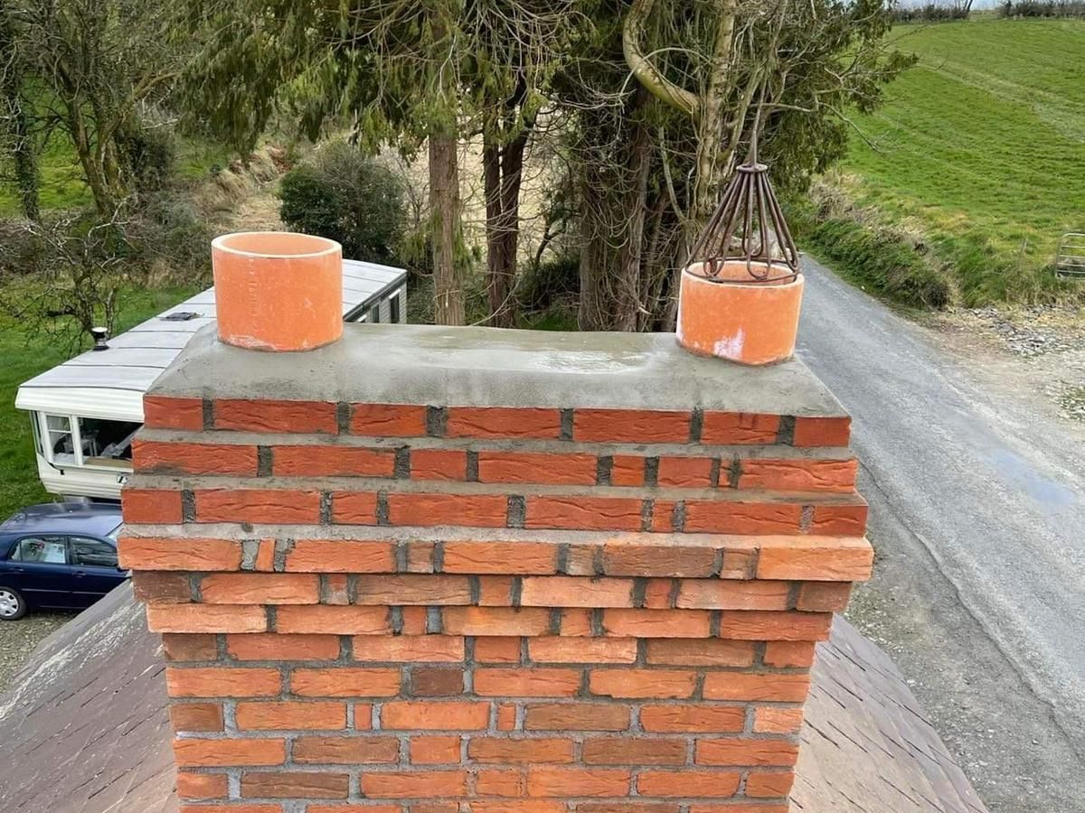A brick chimney is sitting on top of a roof next to a road.