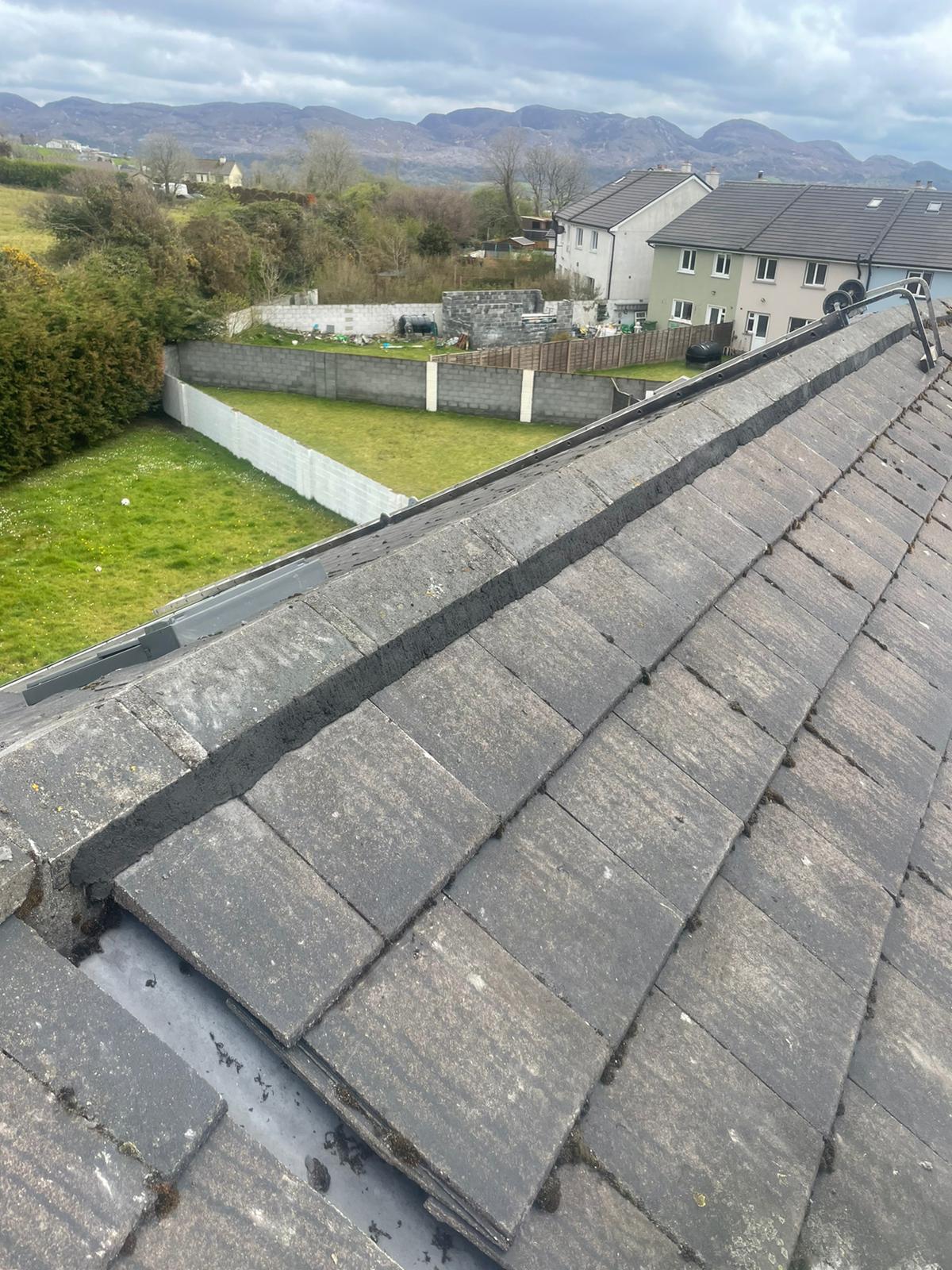 A roof with a lot of tiles on it and a fence in the background.