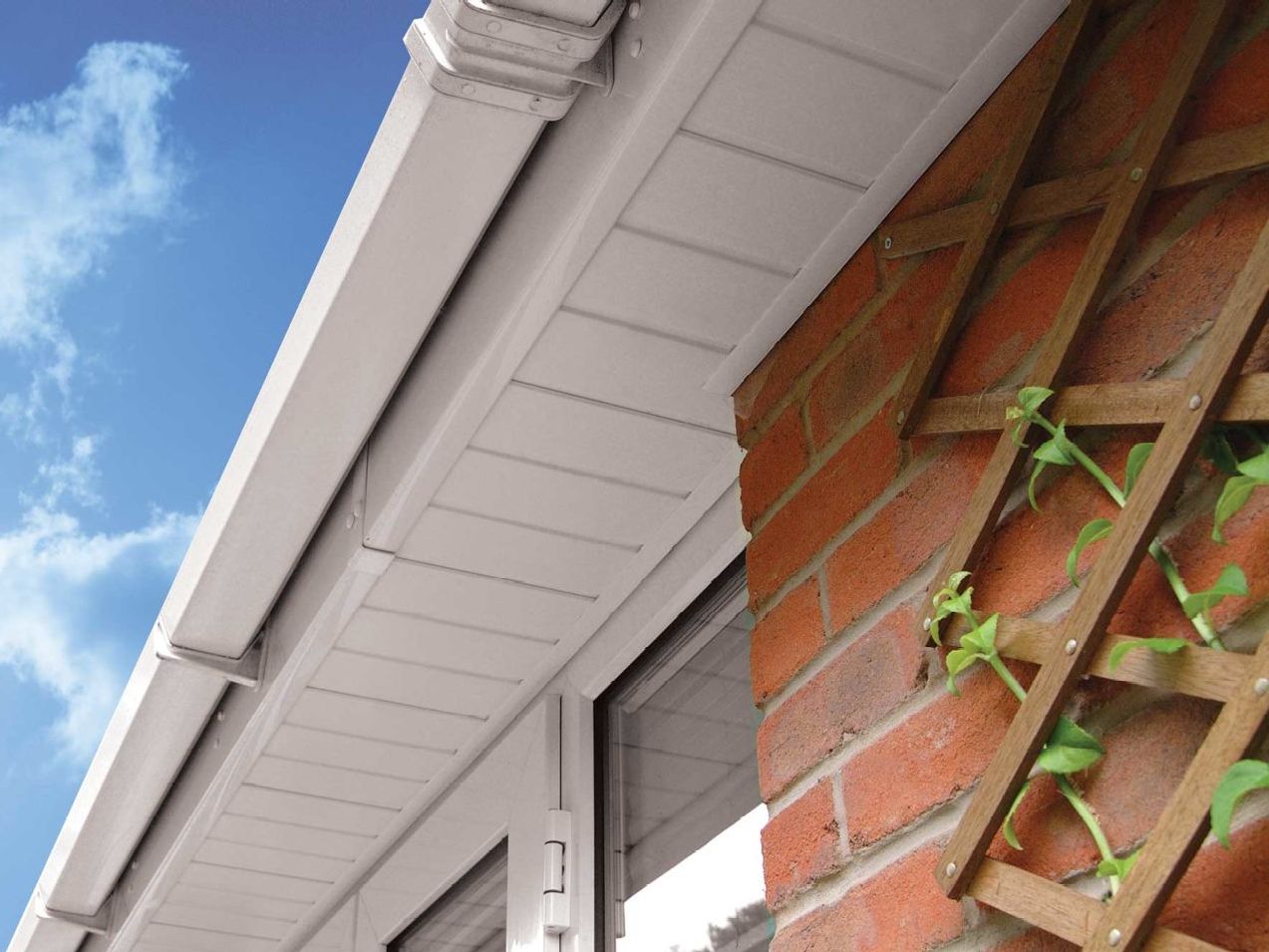 A brick building with a white gutter and a window