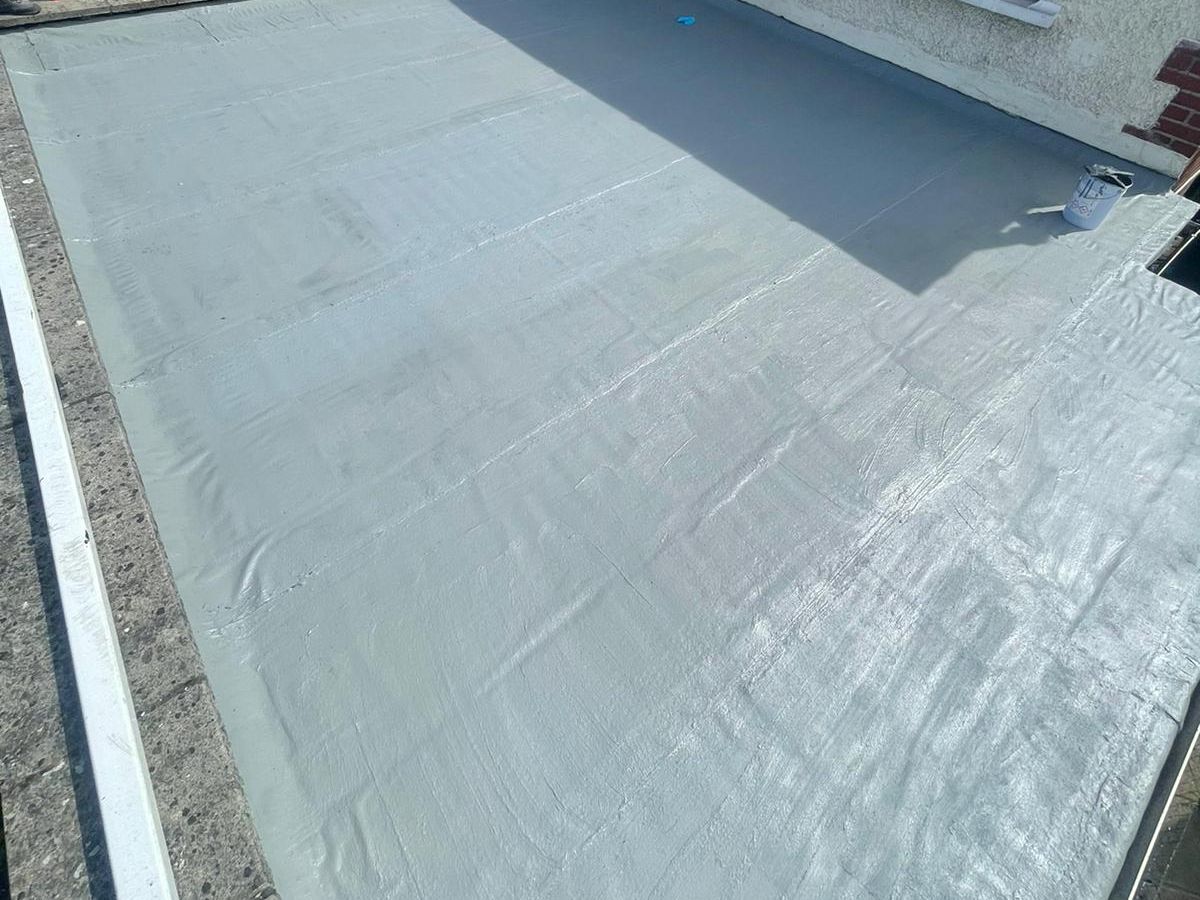 A person is painting a roof with a brush.