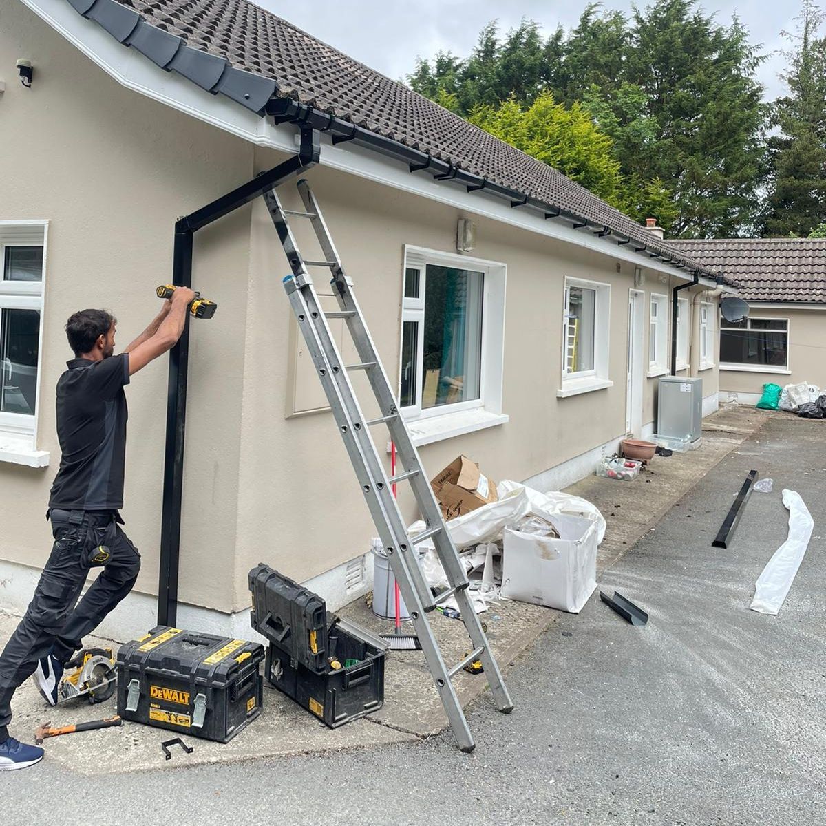 A man is working on the side of a house with a ladder.
