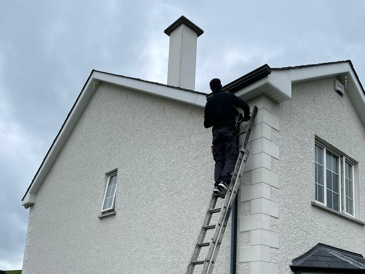 A man is standing on a ladder on the side of a house.