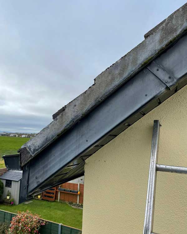A ladder is sitting on the side of a building next to a roof.