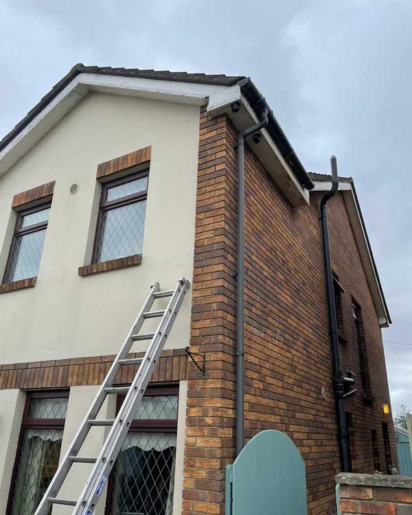 A ladder is sitting on the side of a brick house.
