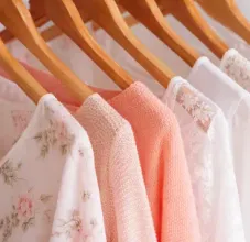 A row of blazers hanging on a rack, featuring various patterns and colors including gingham, beige, and white.
