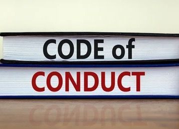 Stacked books with the words “CODE of CONDUCT” on the spines, black and red text on white covers