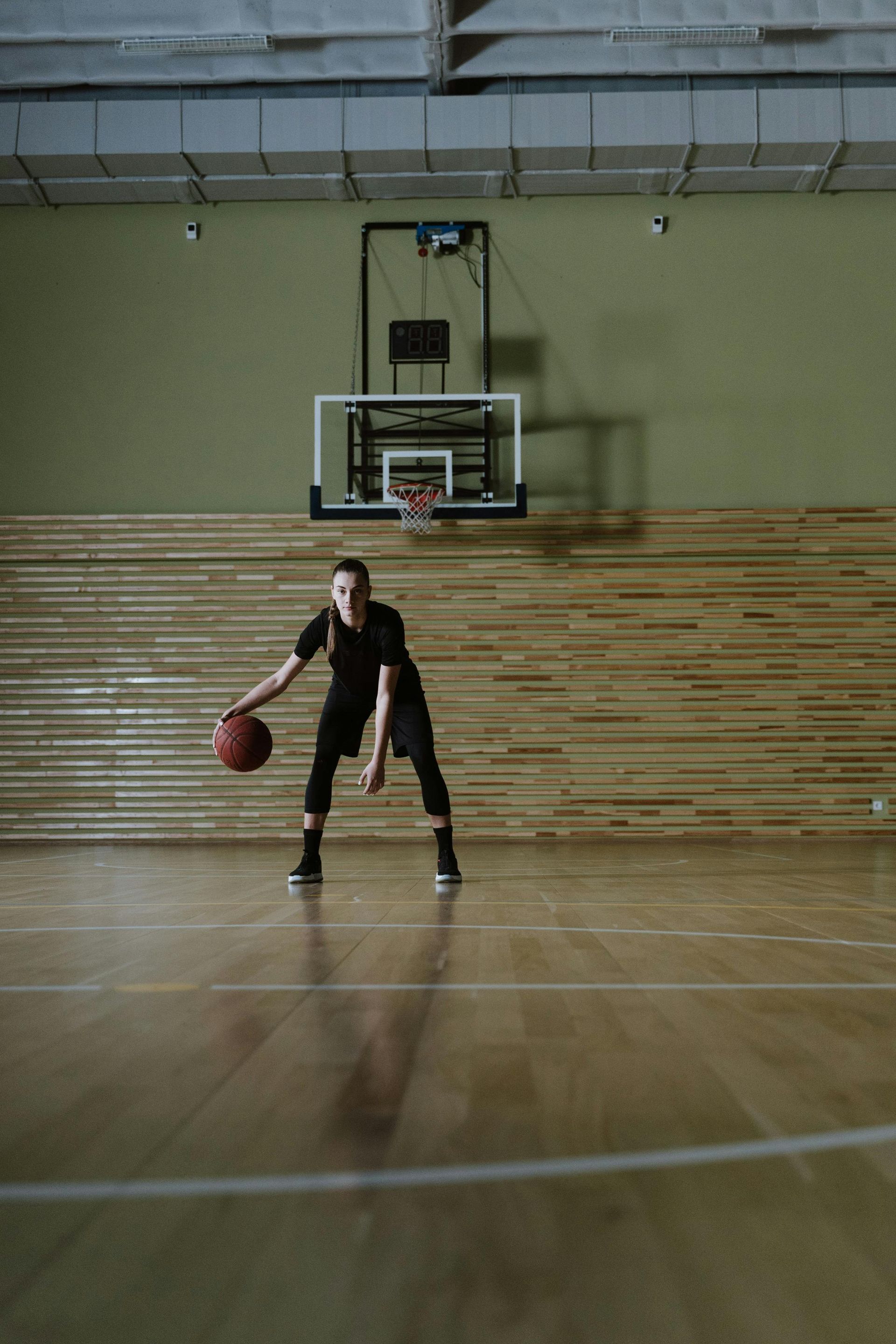 Basketball player dribbling on an indoor court beneath a hoop
