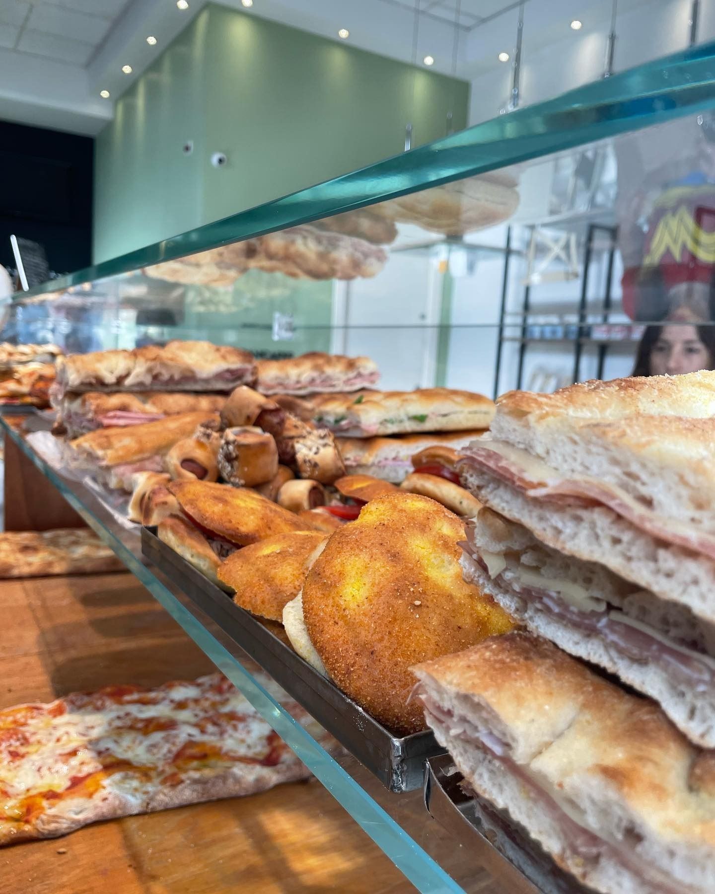 Vetrina con vari prodotti da forno: panini, pizza e pasticcini.