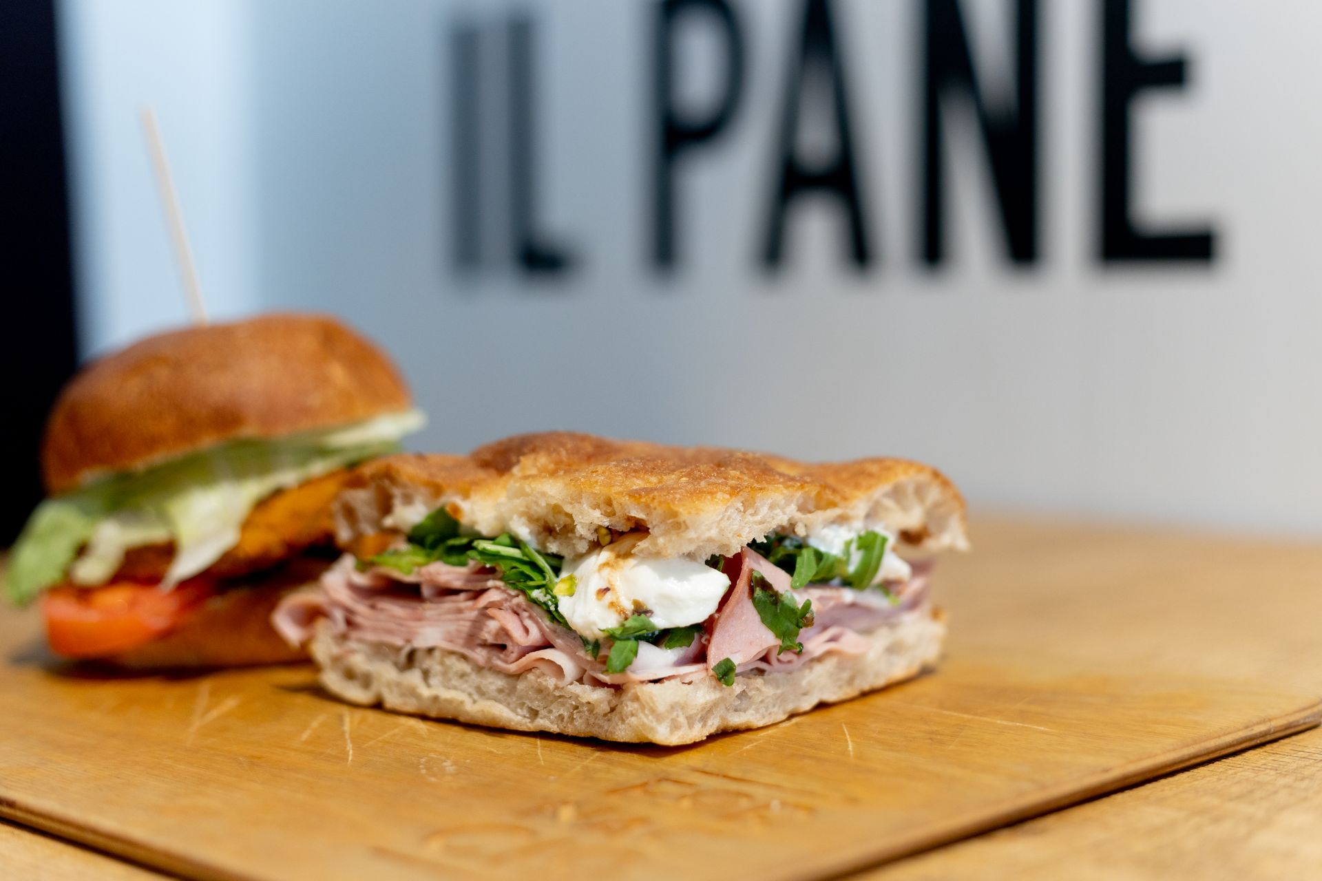 Panino e hamburger su un tagliere di legno davanti al cartello