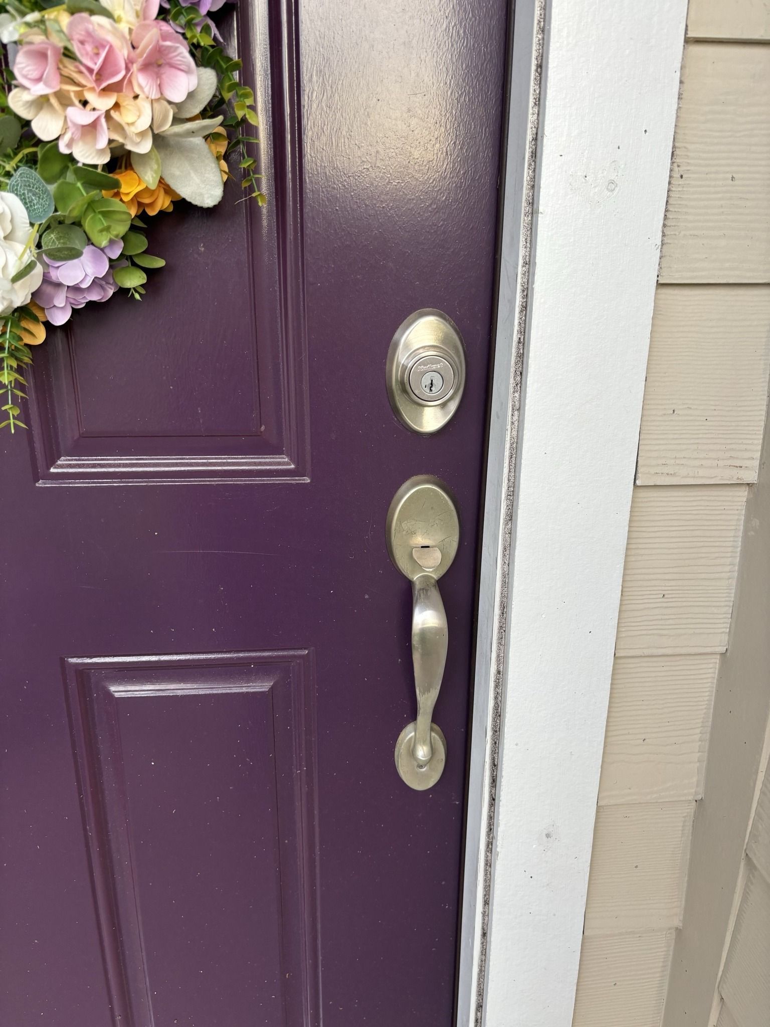 A purple door with a wreath of flowers on it