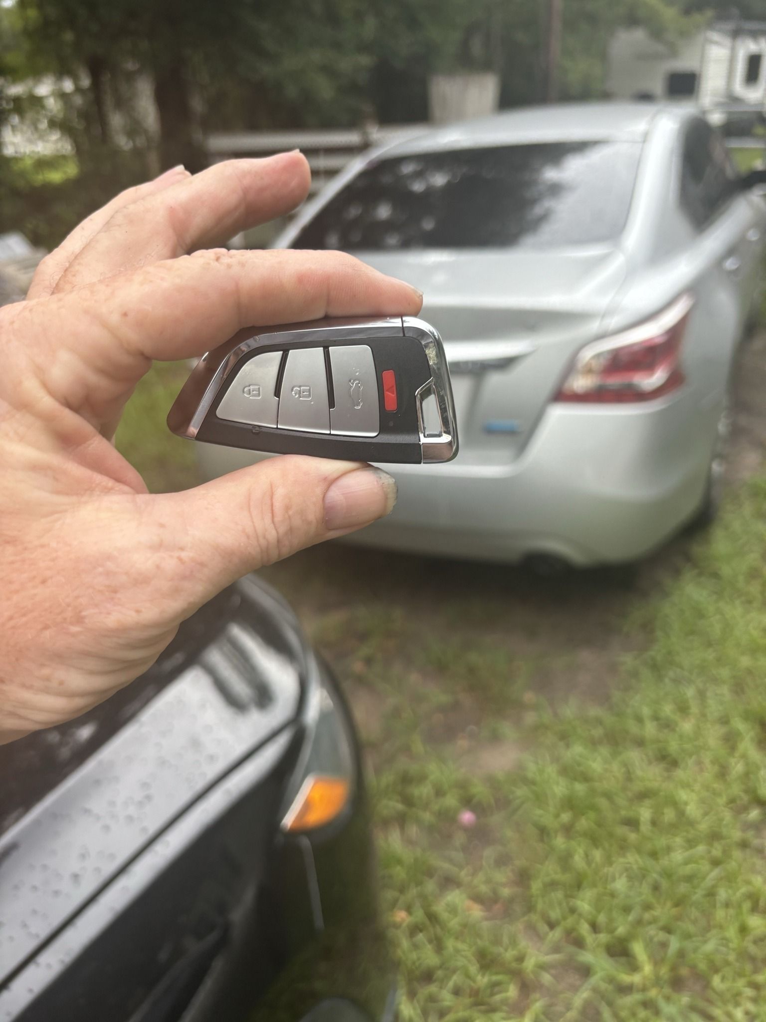 A person is holding a car key in front of a car.