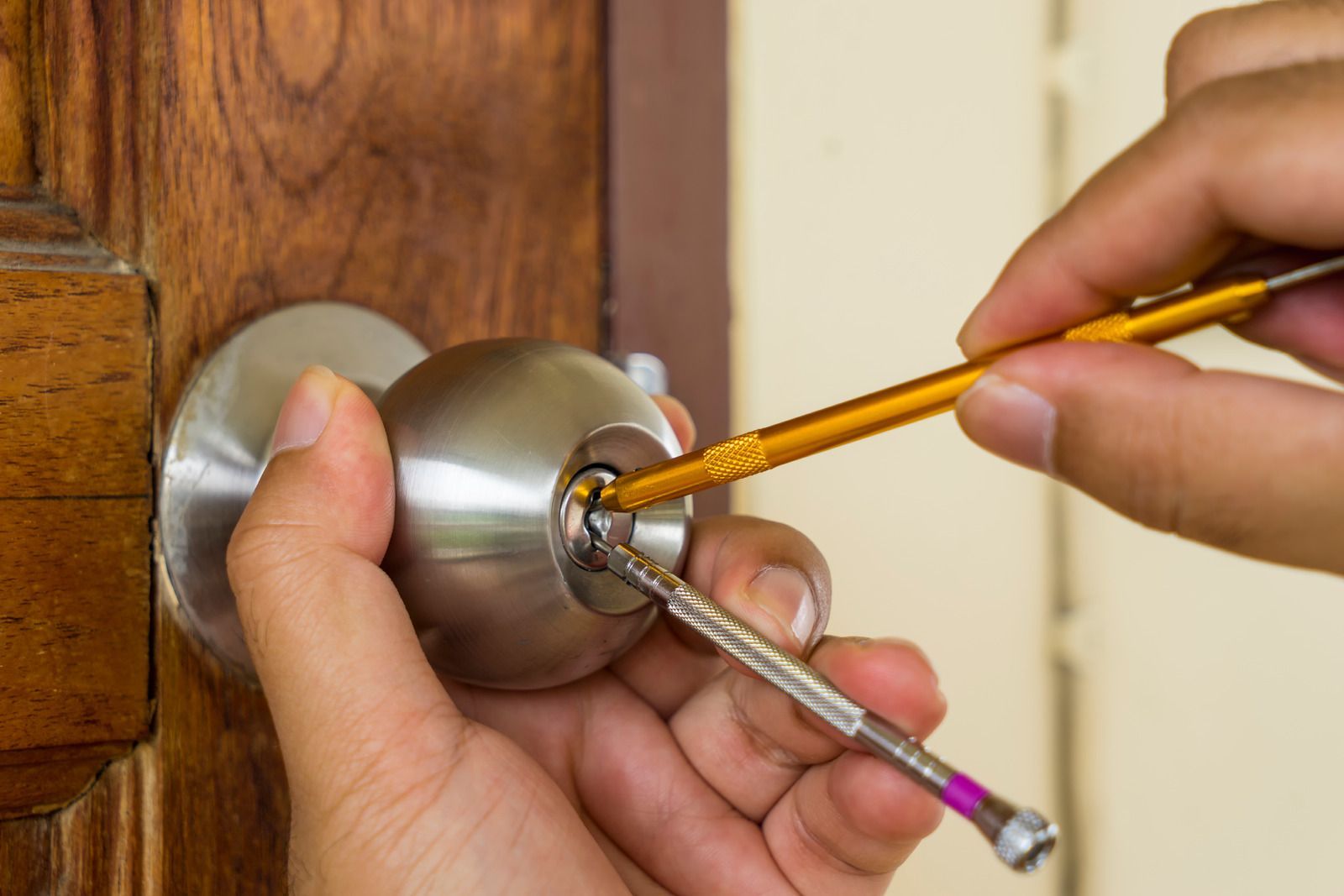 Hands using lock picks to open a door lock.