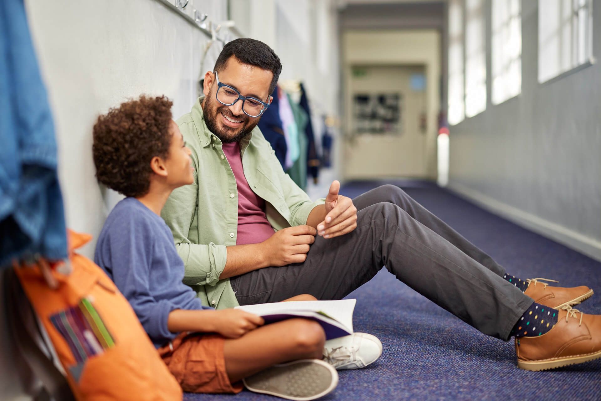 Father and son converse casually in the school hallway.