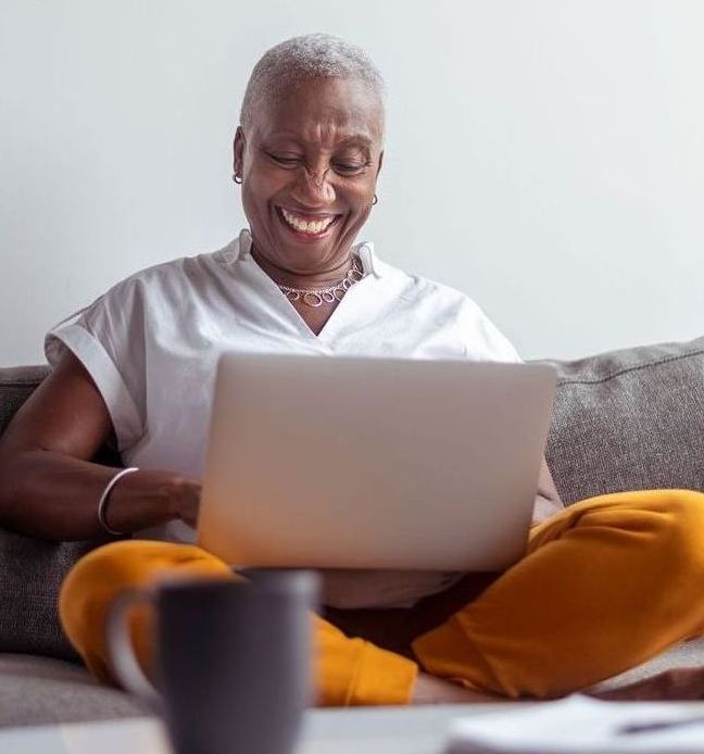 Mature woman smiles at laptop screen at home.