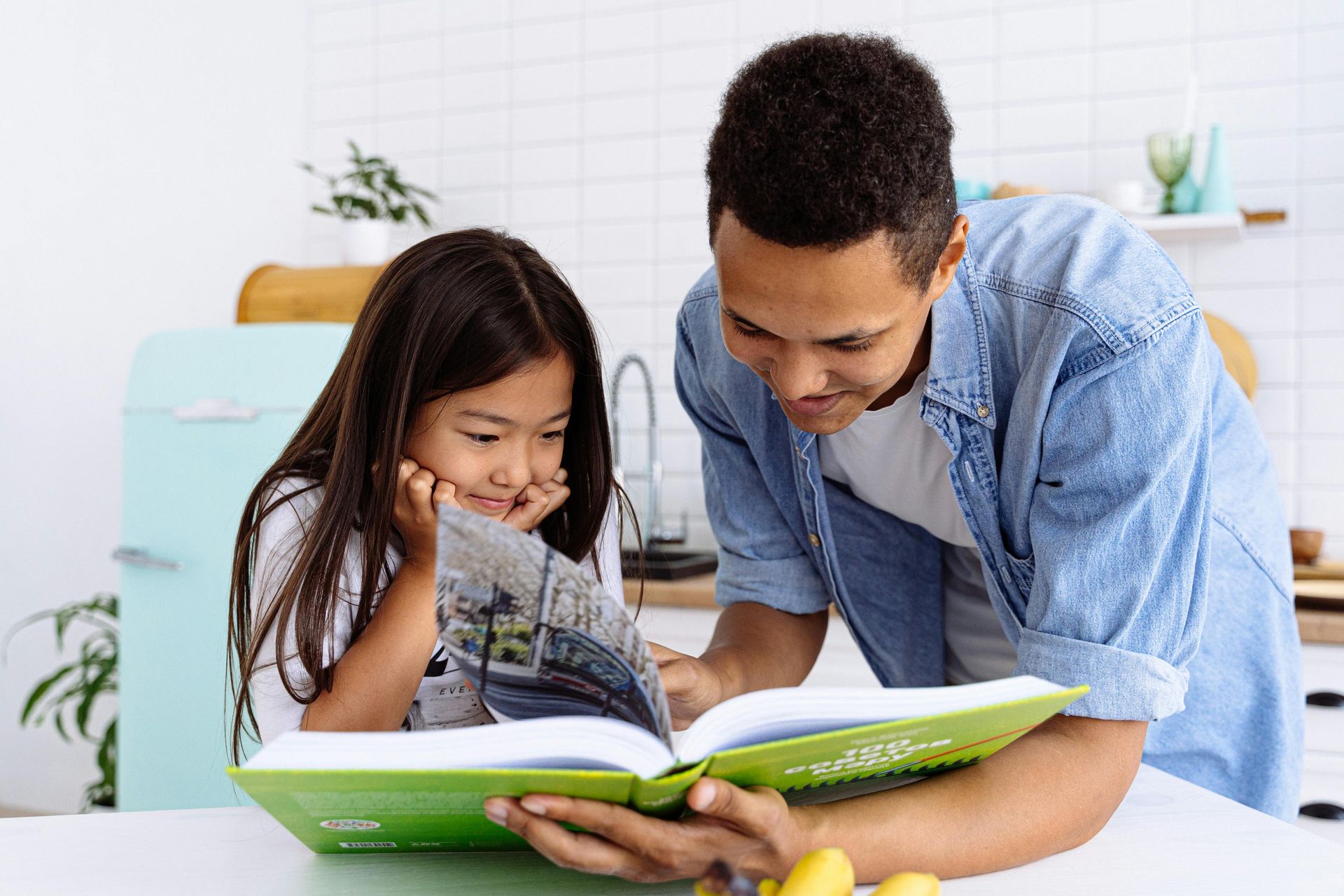 Father and young daughter read a book together.