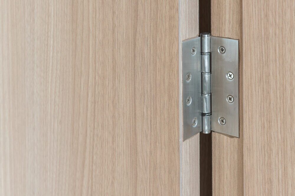 A Metal Door Hinge Attached to a Light-colored Wooden Door — Northco Constructions In Nightcliff, NT