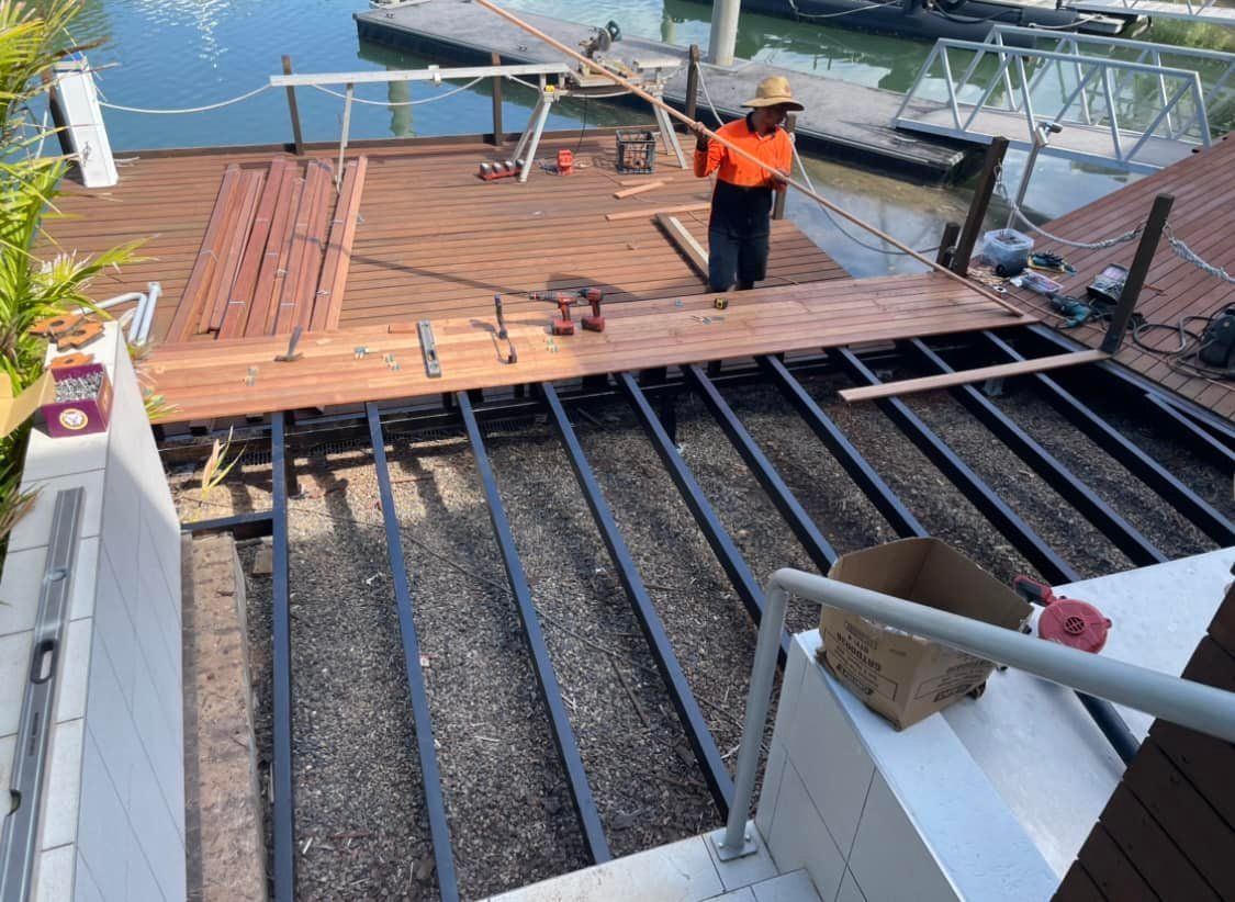 A Person Builds a Wooden Deck Over a Metal Frame Near a Body of Water — Northco Constructions In Muirhead, NT