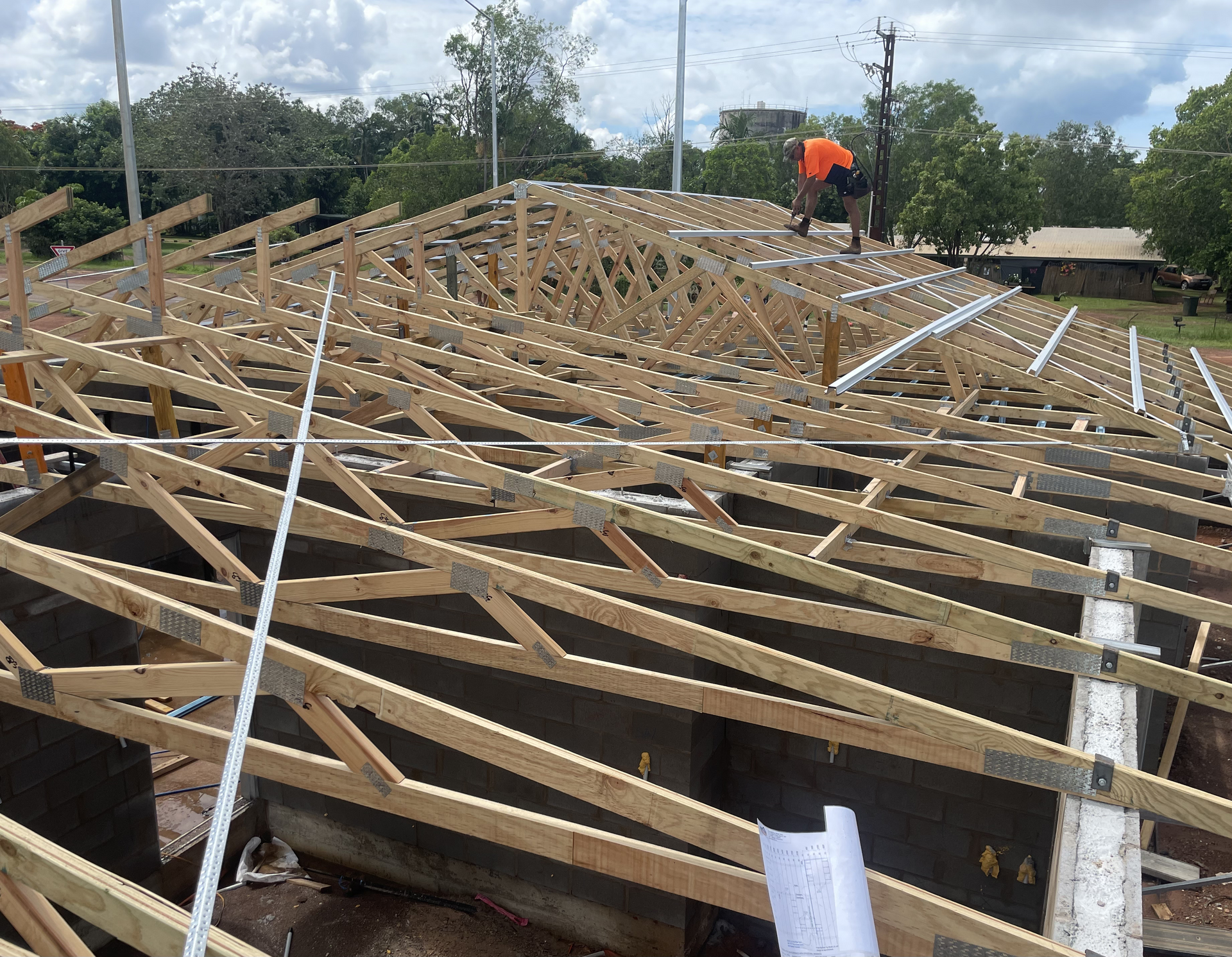Man Building a Wooden Deck Outdoors; He's Kneeling, Wearing Work Clothes, Surrounded by Planks and Tools — Northco Constructions In Muirhead, NT