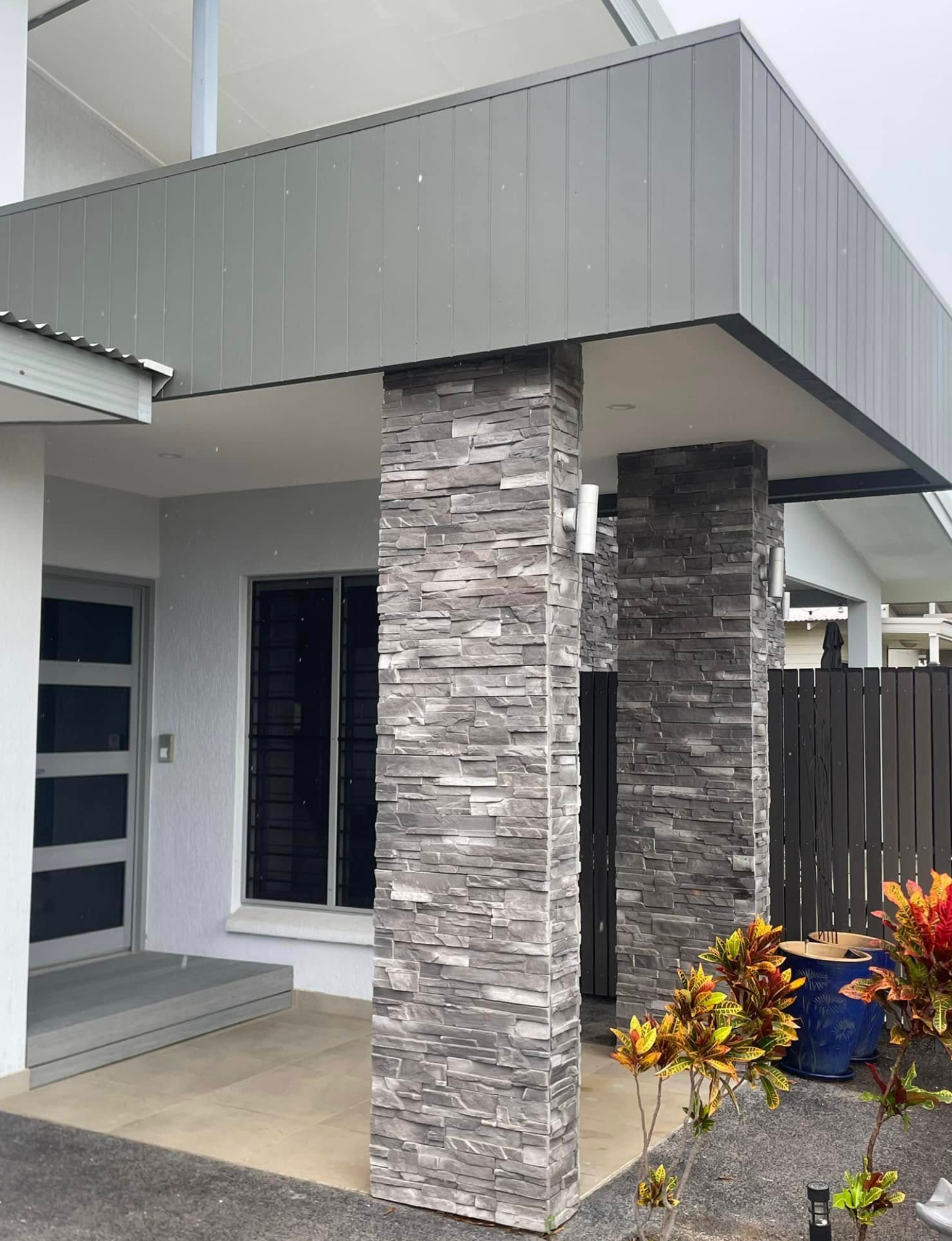Exterior of a Modern House With Gray Stacked Stone Pillars Supporting a Covered Entryway — Northco Constructions In Muirhead, NT