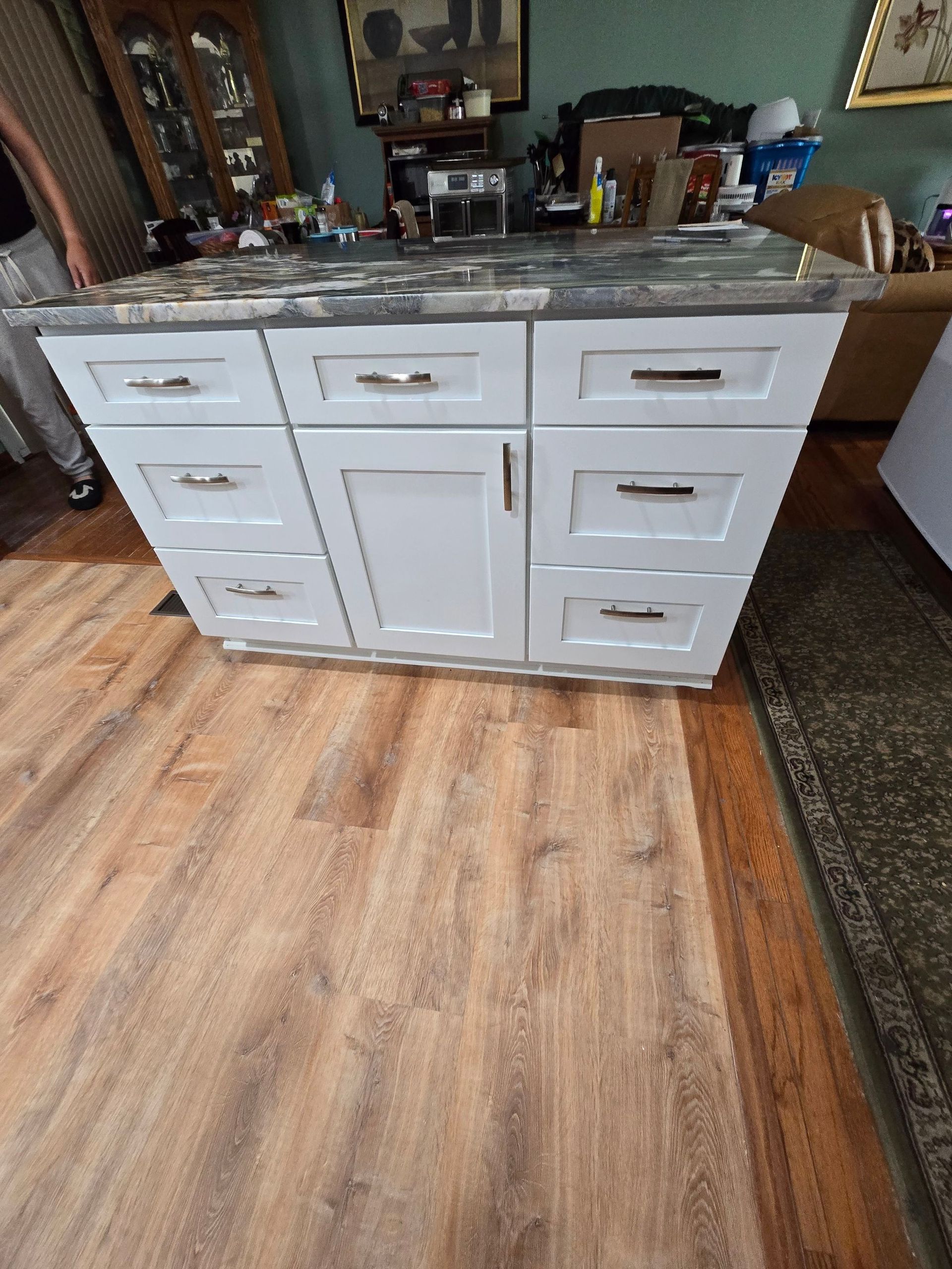 A white cabinet with drawers and a marble counter top in a living room.