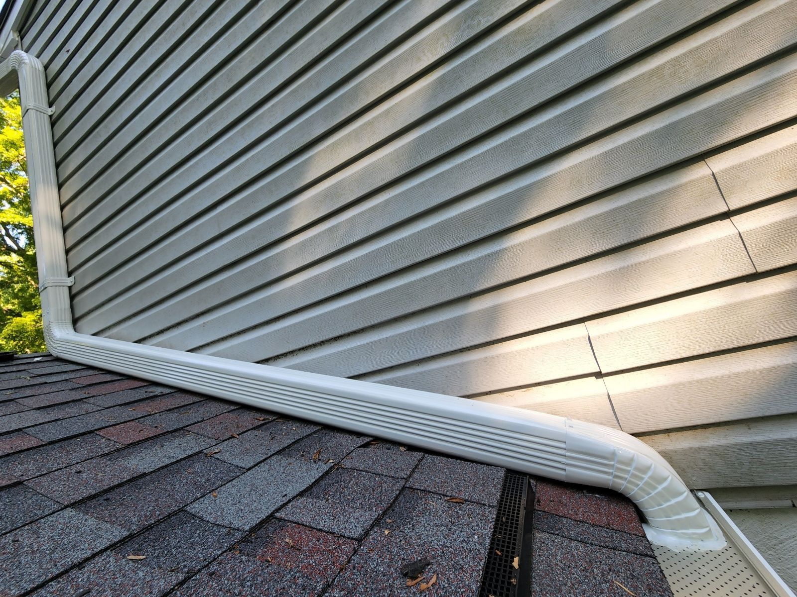 A close up of a gutter on the side of a house.
