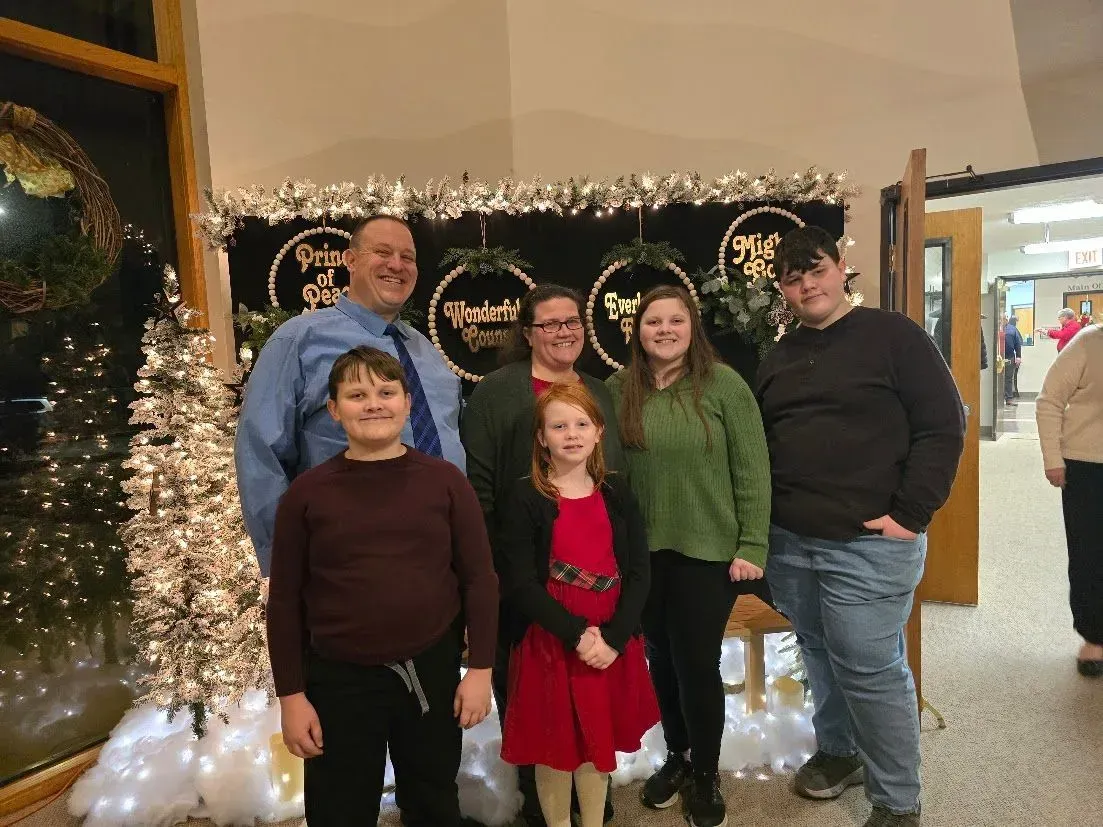 A group of people are posing for a picture in front of a christmas tree.