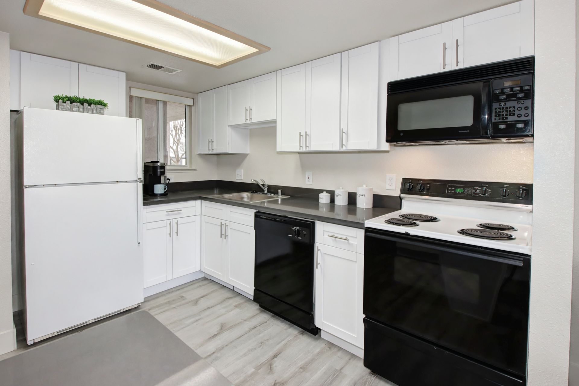 Bright white kitchen with black appliances and countertops.
