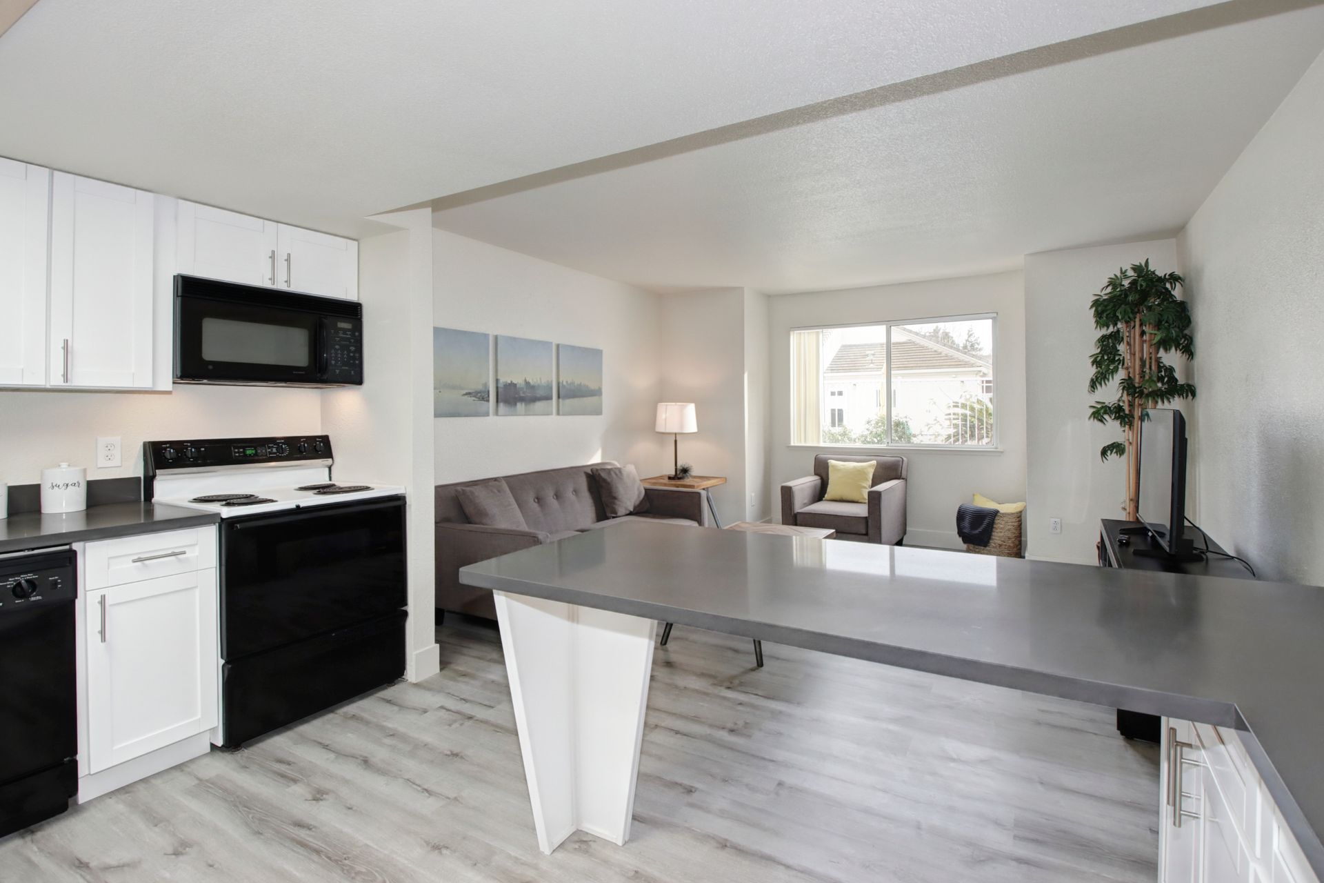 Open-concept kitchen and living area with black appliances, gray countertops, and light gray floors.