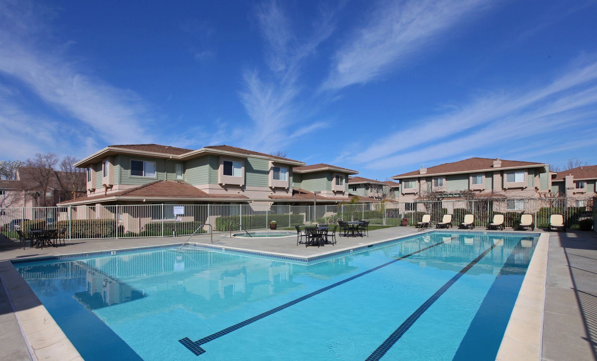 Apartment complex with a blue pool, clear sky overhead.
