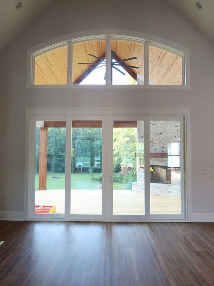 An empty room with a lot of windows and a ceiling fan