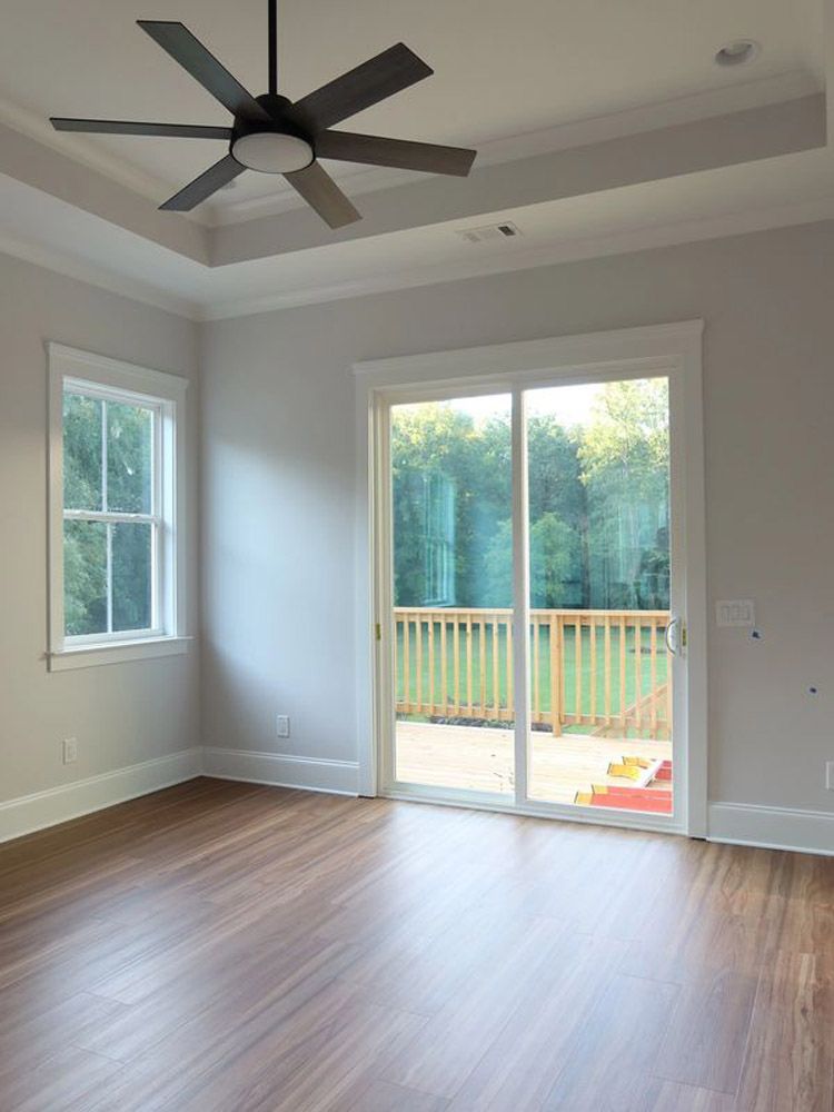 An empty room with a ceiling fan and sliding glass doors