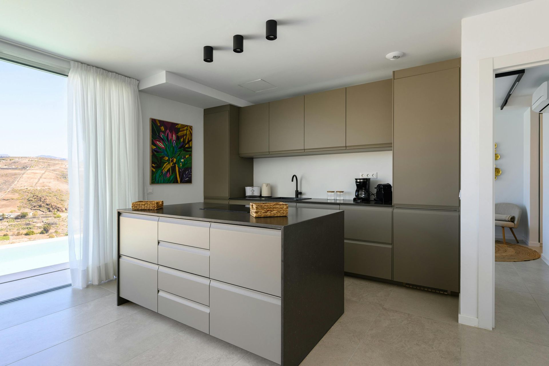 Three black modern flush lighting fixtures mounted to a kitchen ceiling above the island. 