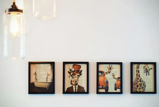 White wall in a house with four framed pictures hanging on the wall.
