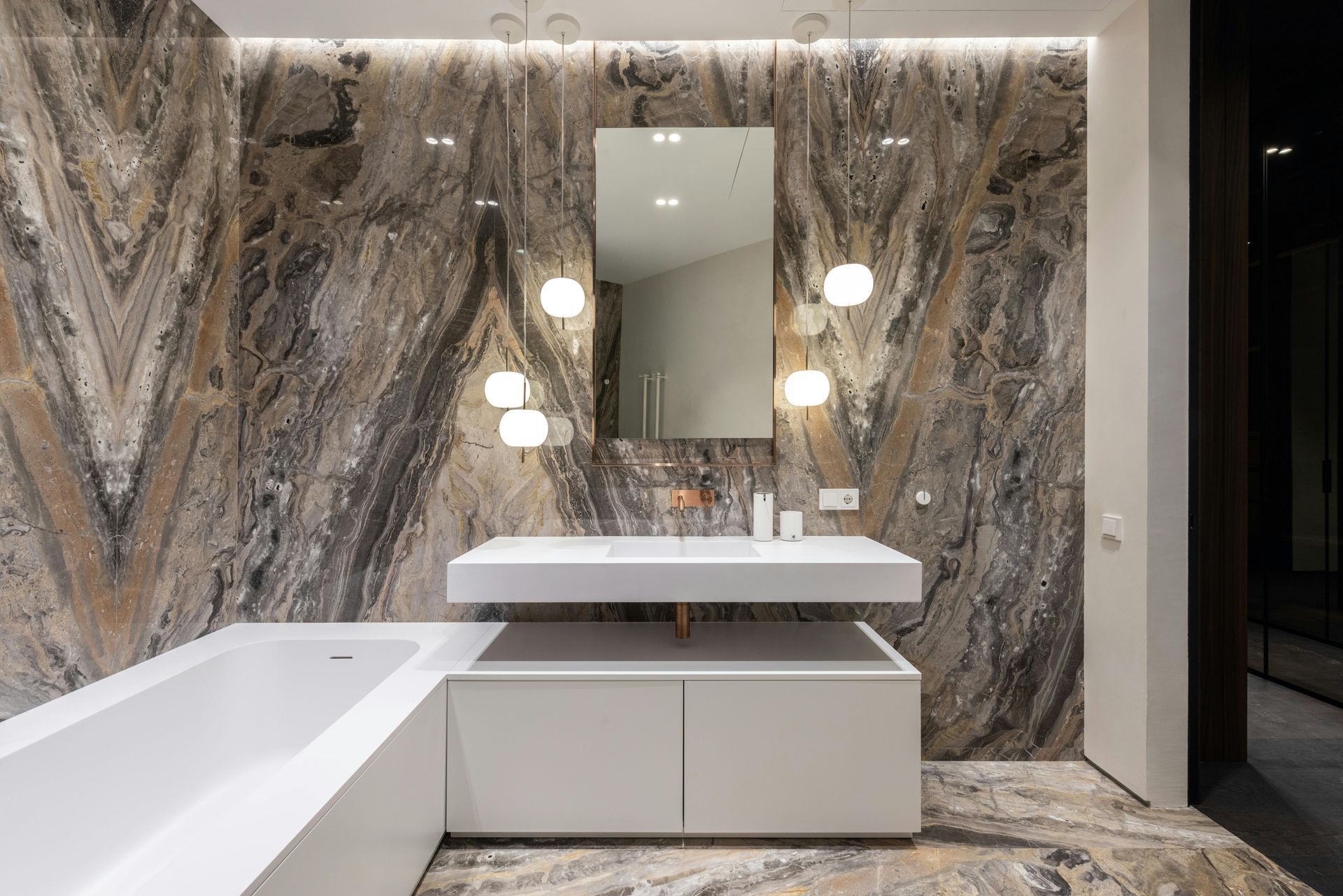 bathroom with oversized white tub, round pendant lighting, a rectangular mirror, and a white sink with cabinets underneath.