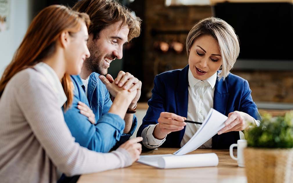A woman is sitting at a table talking to a man and woman.