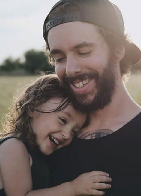 A man with a beard is holding a little girl in his arms.