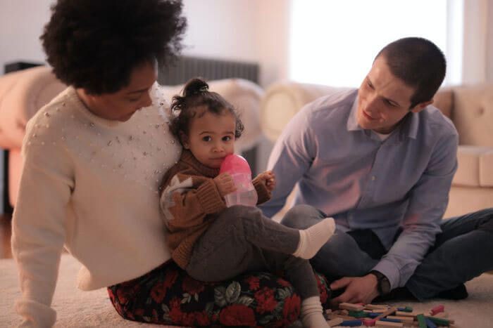 A man and a woman are sitting on the floor with a baby.