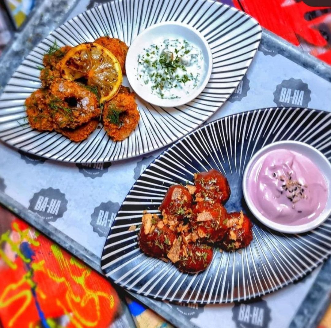 Two plates of fried food with dips on a tray, striped plates, colorful setting.