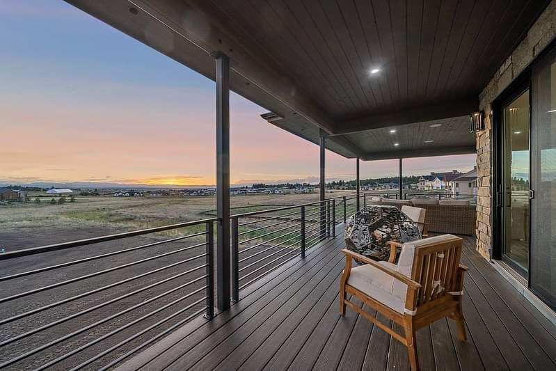 Covered deck with wooden chair overlooking a sunset view over open fields